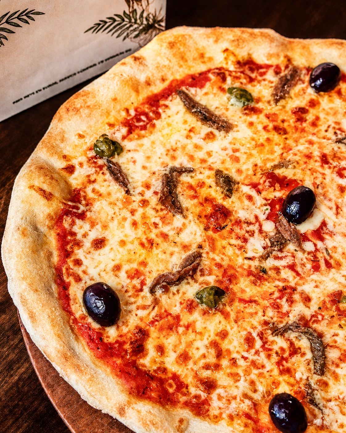 Pizza napolitaine cuite au feu, olives et anchois, servie au Regent
